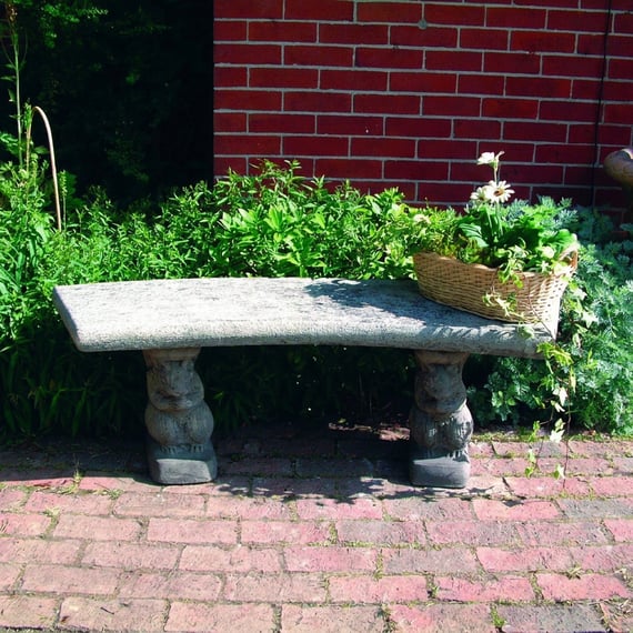 Curved Plain Stone Garden Bench in a garden setting with brick paving and greenery