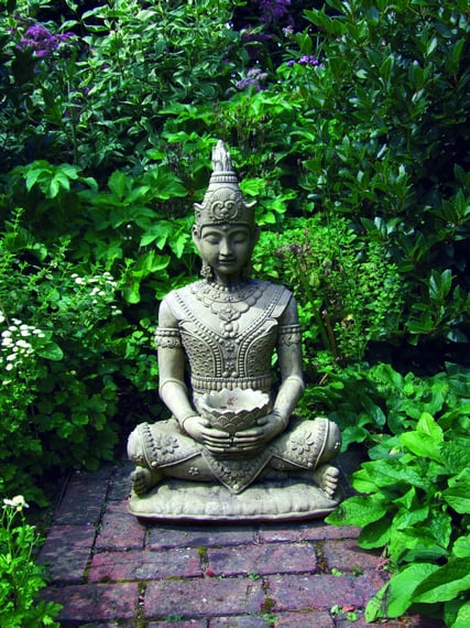 Serene Buddha stone fountain in stone finish sat on a brick garden path