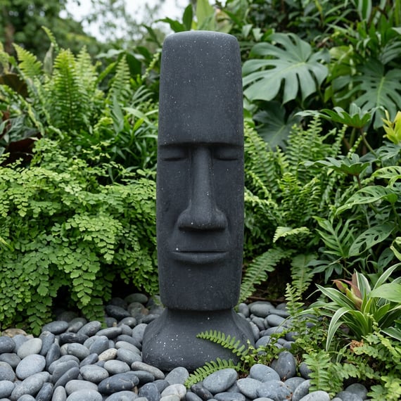 Easter Island Garden Statue in Black in a lush garden setting with ferns and pebbles