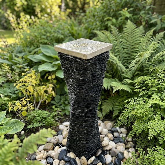 Twisted slate column water feature in a planted garden setting