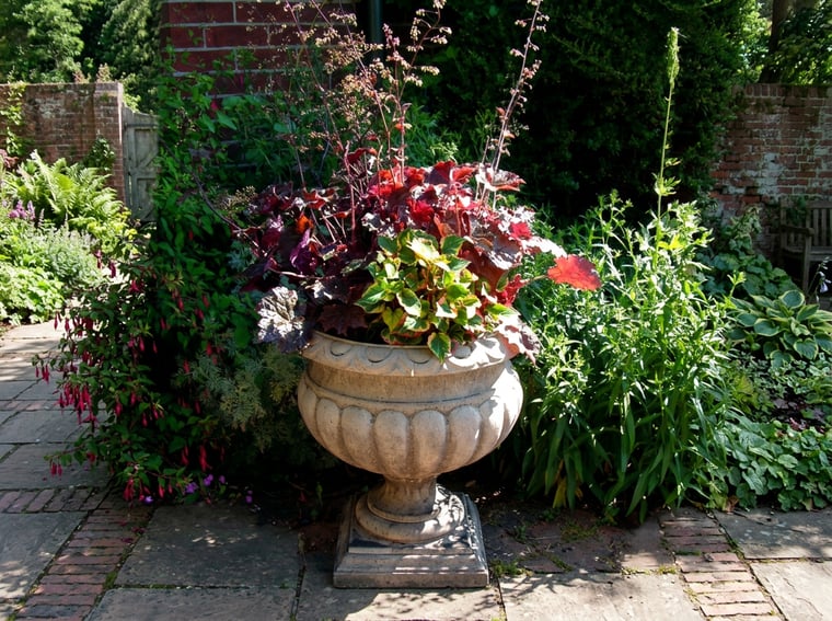 Large Buckingham fluted stone garden urn used as a planted focal point in a formal garden